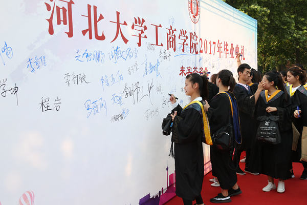 畢業(yè)生在簽名墻前簽名